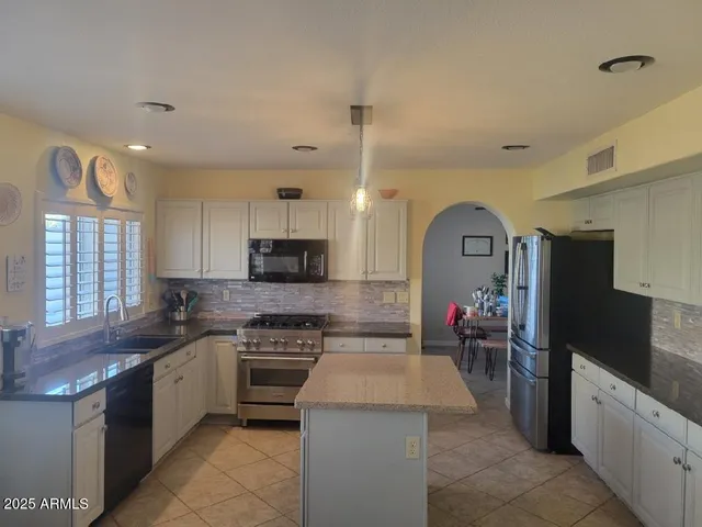 a kitchen with granite countertop a refrigerator and white cabinets