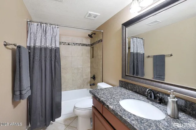 a bathroom with a granite countertop sink a toilet and shower
