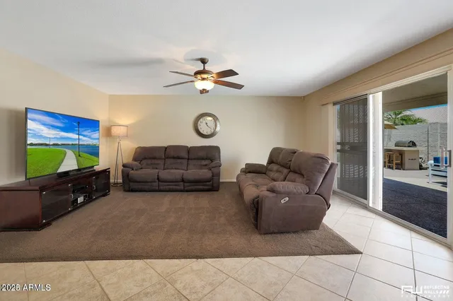 a living room with furniture a flat screen tv and a large window