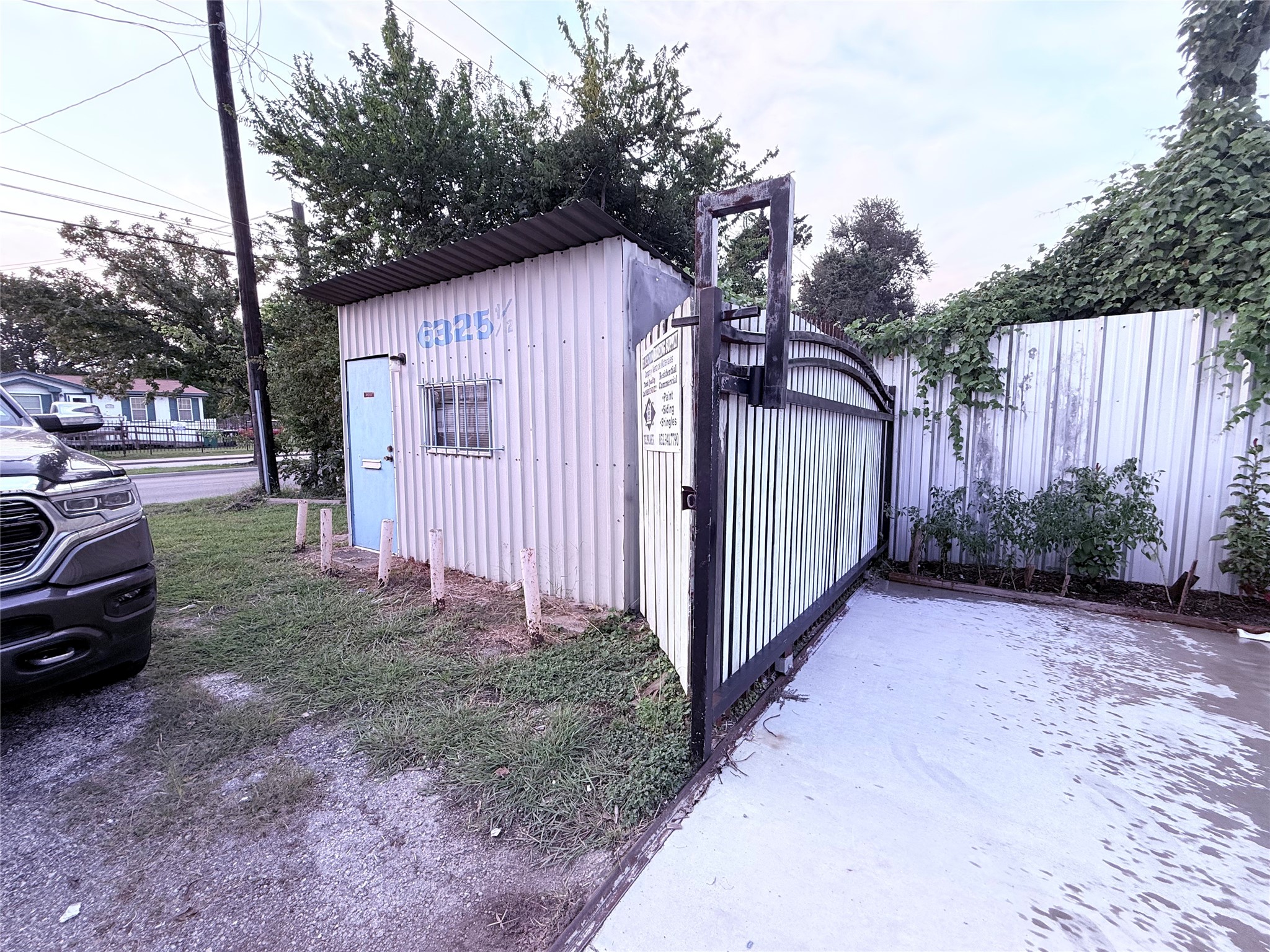 6325 Cullen Boulevard Houston, TX 77021 - Photo 11 of 18 This photo shows a small, corrugated metal structure with a gated entrance, located on a grassy area near a road. It appears to have a basic setup, with a simple design and some surrounding greenery.