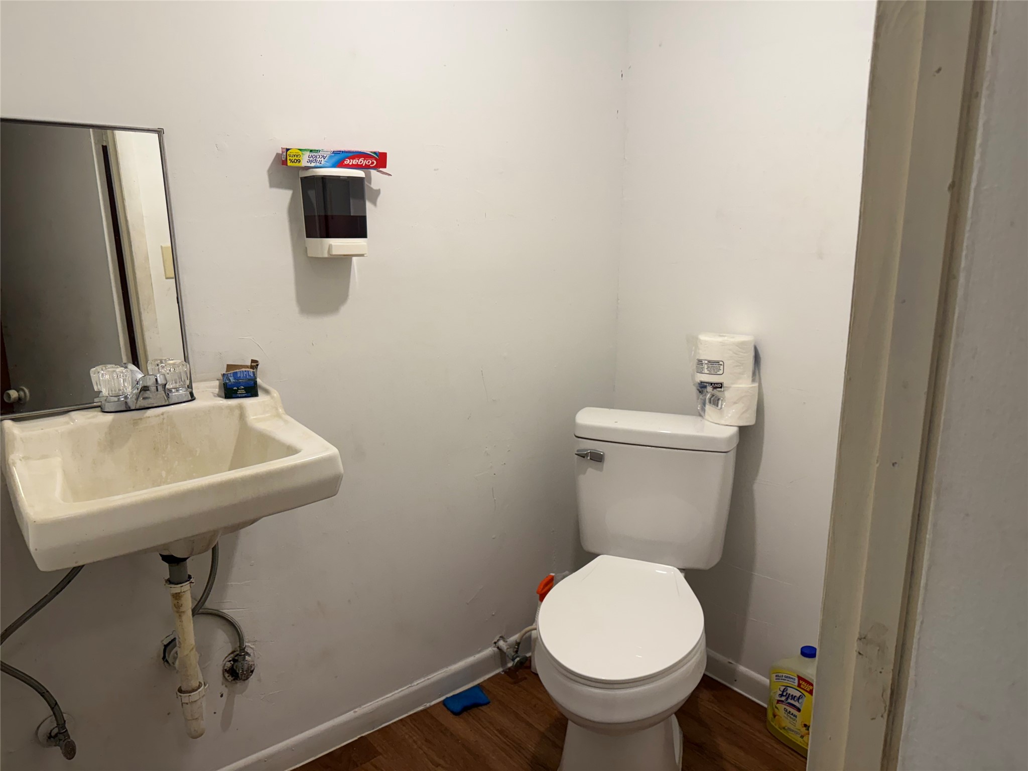6325 Cullen Boulevard Houston, TX 77021 - Photo 16 of 18 A compact bathroom with a white sink and mirror, a toilet, and simple white walls. The space includes basic fixtures and laminate flooring, ideal for a small home or guest bathroom.