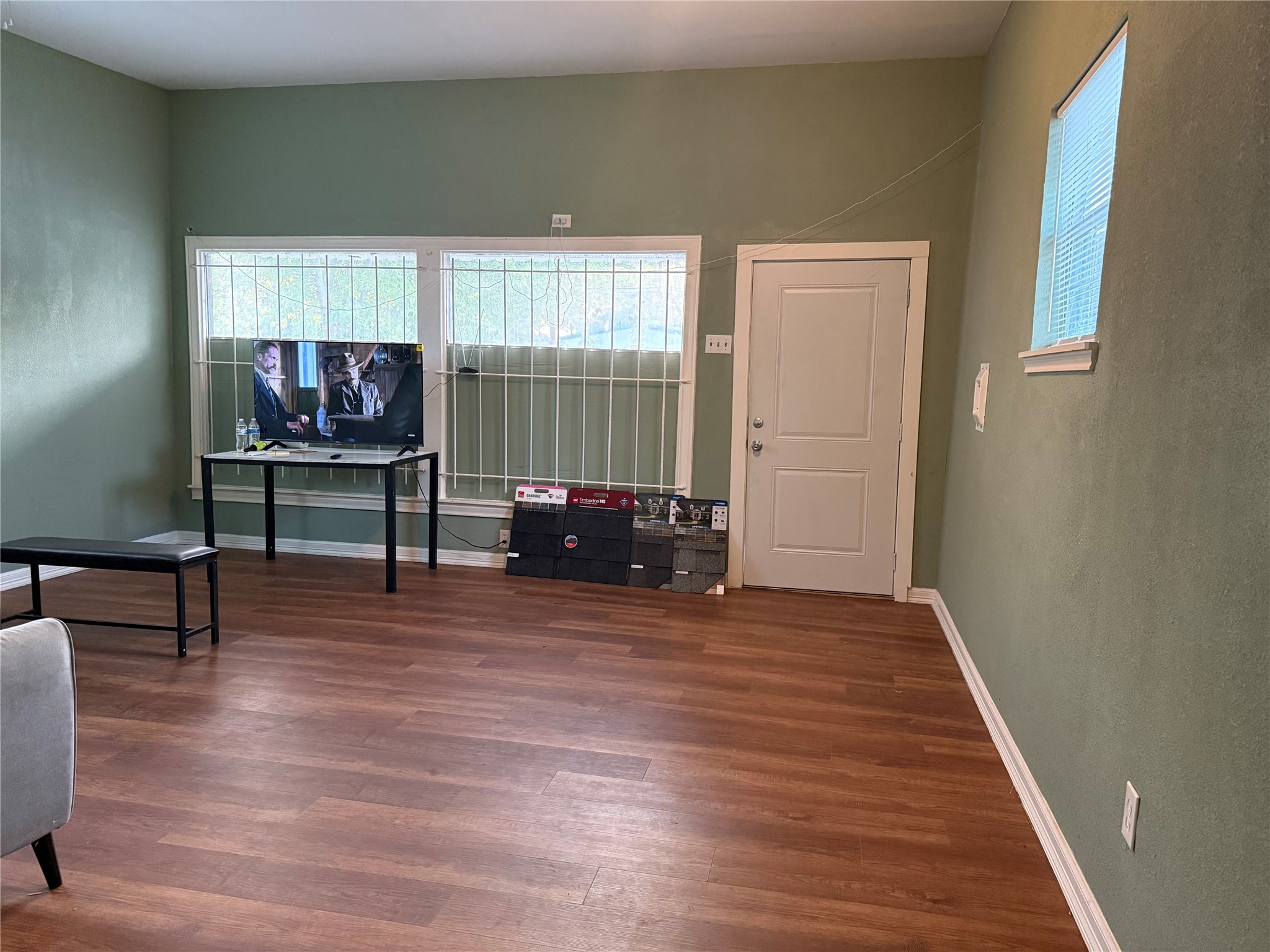 6325 Cullen Boulevard Houston, TX 77021 - Photo 18 of 18 Spacious living area with green walls, hardwood floors, and ample natural light from large windows. Ideal for cozy gatherings and relaxation.