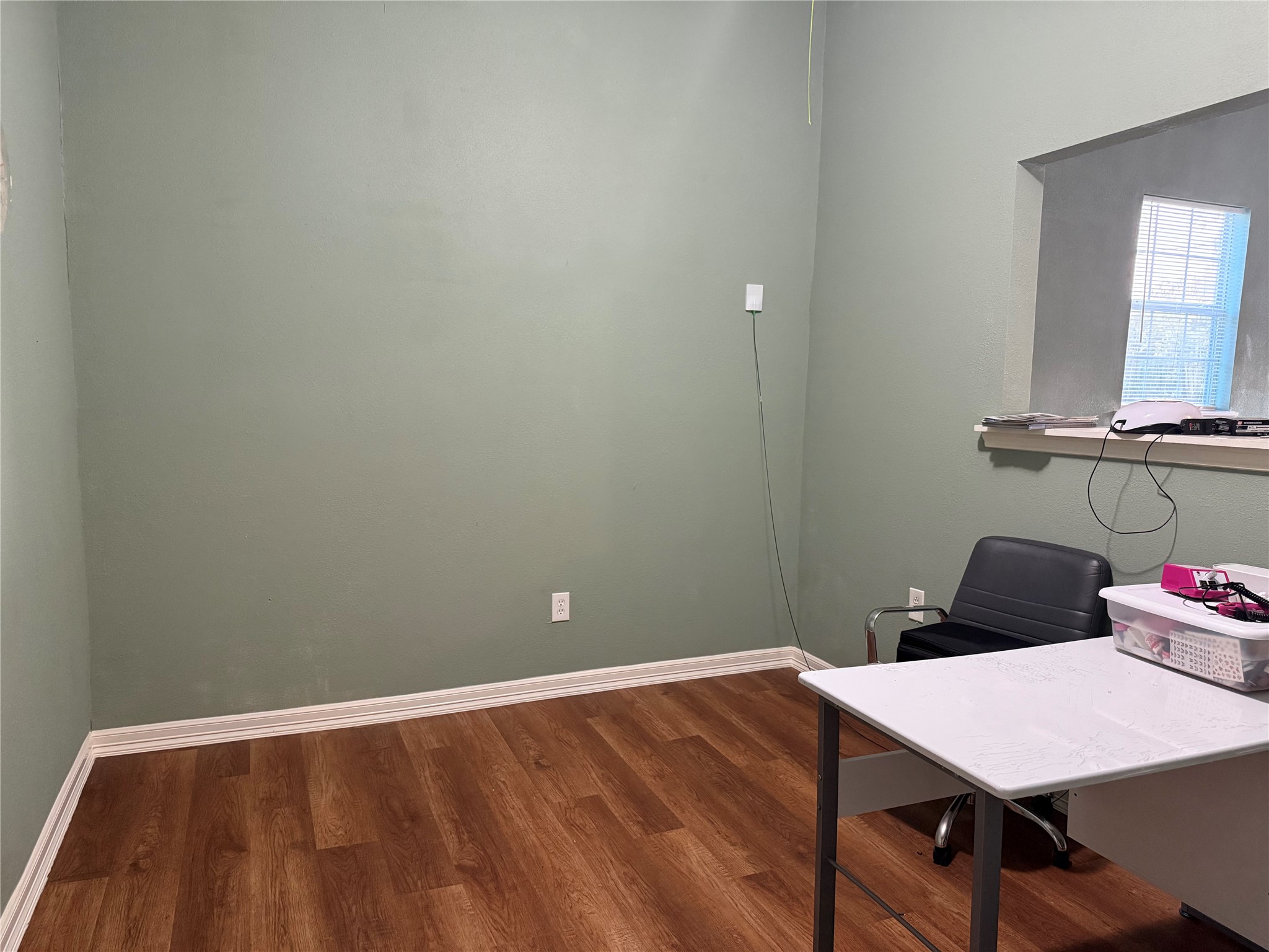 6325 Cullen Boulevard Houston, TX 77021 - Photo 6 of 18 This room features light green walls, wood flooring, and a small window for natural light. It includes a simple desk and chair setup, ideal for a home office or study space.