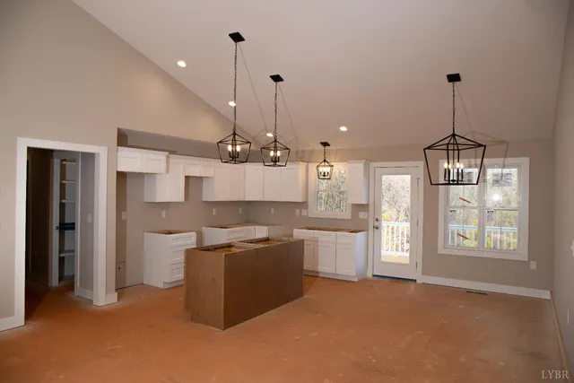 a open kitchen with stainless steel appliances granite countertop a refrigerator a sink dishwasher a oven and a dining table with wooden floor