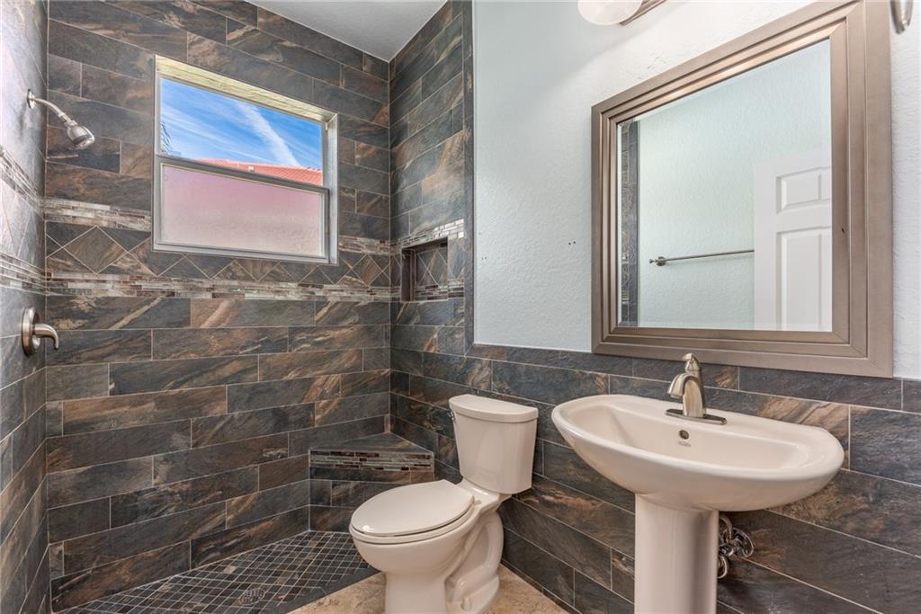 2103 Northwest Marsh Rabbit Lane Stuart, FL 34994 - Photo 17 of 20 a bathroom with a sink a toilet and a mirror
