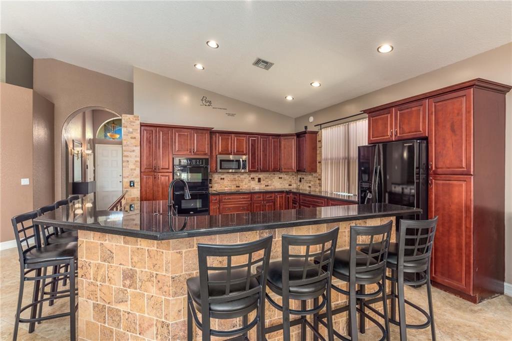 2103 Northwest Marsh Rabbit Lane Stuart, FL 34994 - Photo 8 of 20 a kitchen with stainless steel appliances granite countertop a table and chairs