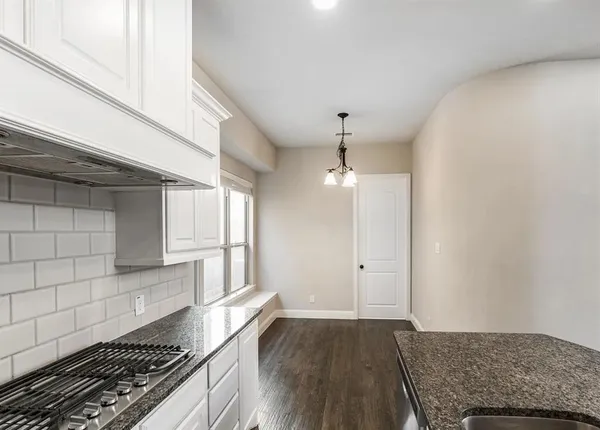 a kitchen with granite countertop a stove and a wooden floor