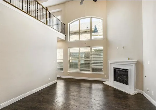 a view of an empty room with wooden floor fireplace and a window