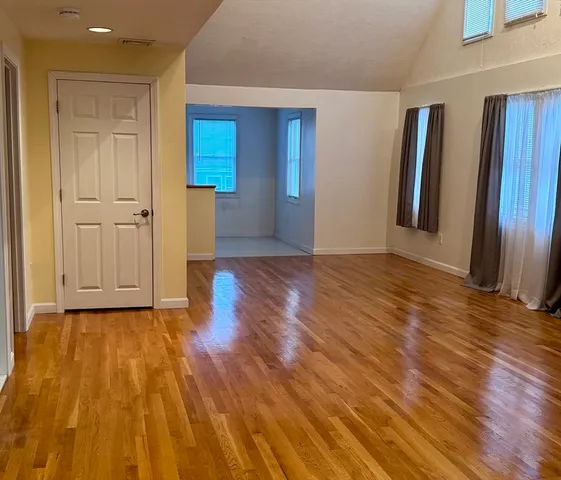 a view of an empty room with wooden floor and closet