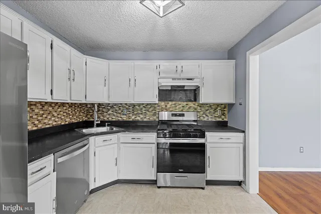 a kitchen with white cabinets stainless steel appliances and sink