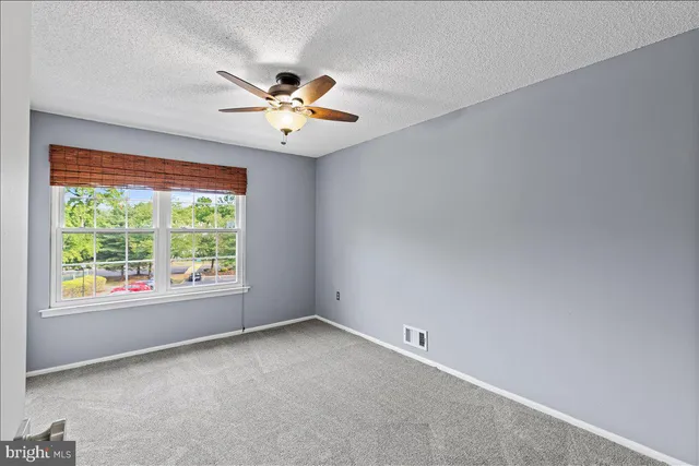 an empty room with a window and a fan