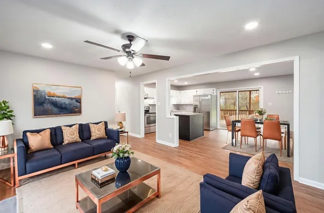 a living room with furniture kitchen view and a wooden floor