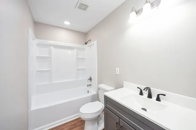 a bedroom with a bed a tv and wooden floor