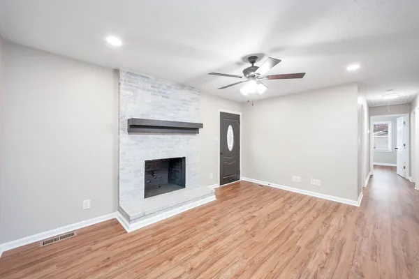 a view of an empty room with wooden floor and a fireplace