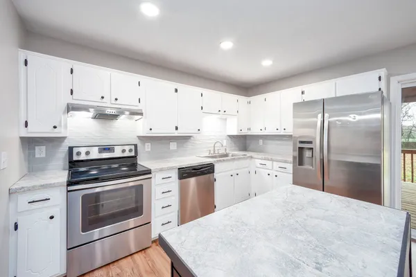 a kitchen with granite countertop white cabinets and stainless steel appliances