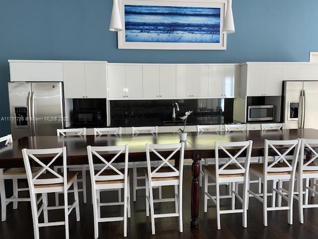 2775 Northeast 187th Street, Unit 311 Aventura, FL 33180 - Photo 22 of 28 a kitchen with a dining table chairs and white cabinets