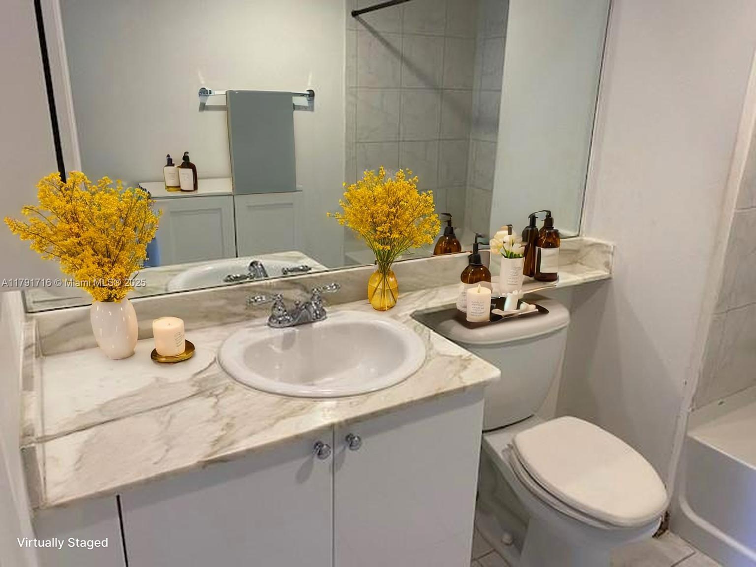 2775 Northeast 187th Street, Unit 311 Aventura, FL 33180 - Photo 6 of 28 a bathroom with a toilet sink and mirror