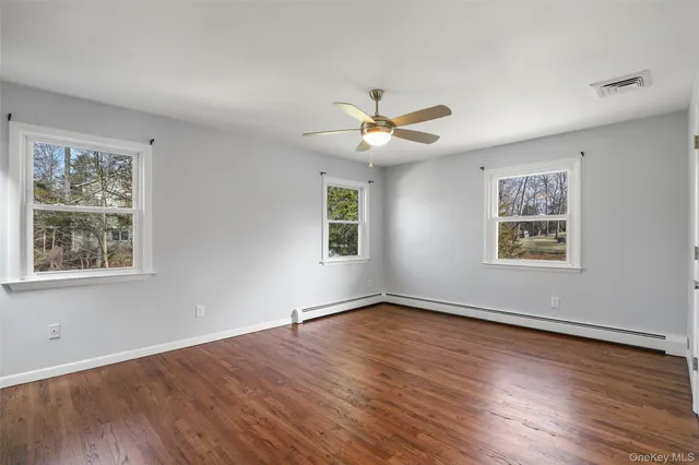 a view of an empty room with a window and wooden floor
