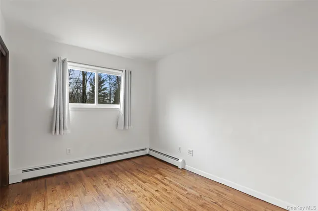 a view of empty room with wooden floor and window