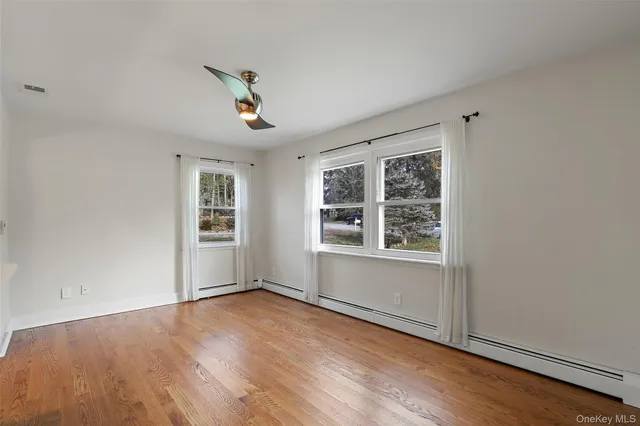 an empty room with wooden floor fireplace and windows