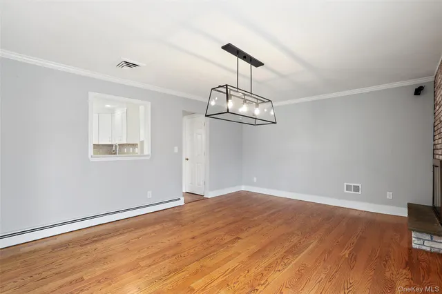 a view of an empty room with wooden floor fireplace and a window