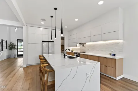 a kitchen with stainless steel appliances granite countertop a table chairs stove a refrigerator and a dining table with wooden floor