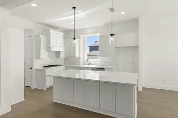 a kitchen with stainless steel appliances granite countertop a sink a stove a refrigerator and white cabinets with wooden floor