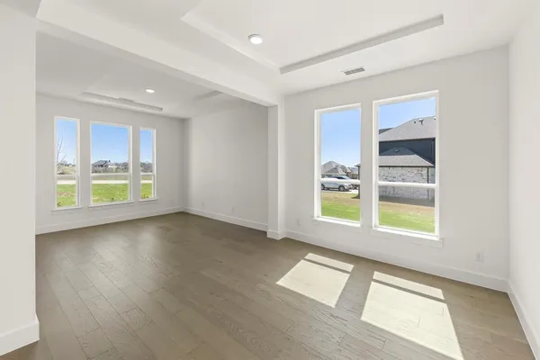 a view of an empty room with a window and wooden floor