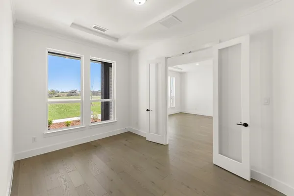 a view of an empty room with a window and wooden floor