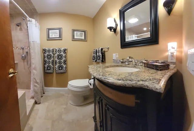 a bathroom with a granite countertop sink toilet and a mirror