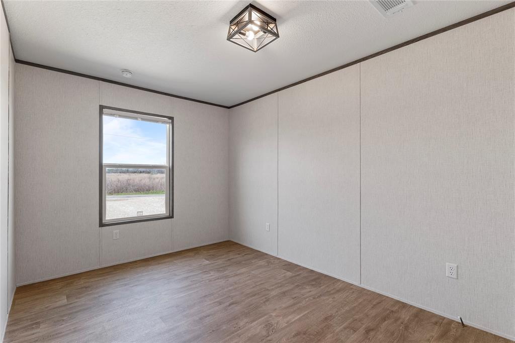3888 Sandusky Road Whitesboro, TX 76273 - Photo 17 of 24 Spare room with ornamental molding, light wood-style floors, and a textured ceiling