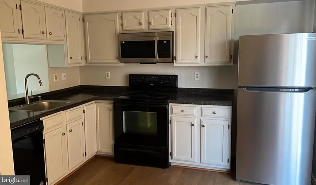 a kitchen with granite countertop white cabinets and refrigerator