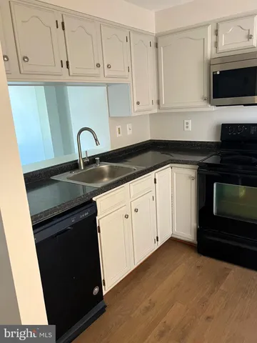 a kitchen with granite countertop white cabinets and black appliances