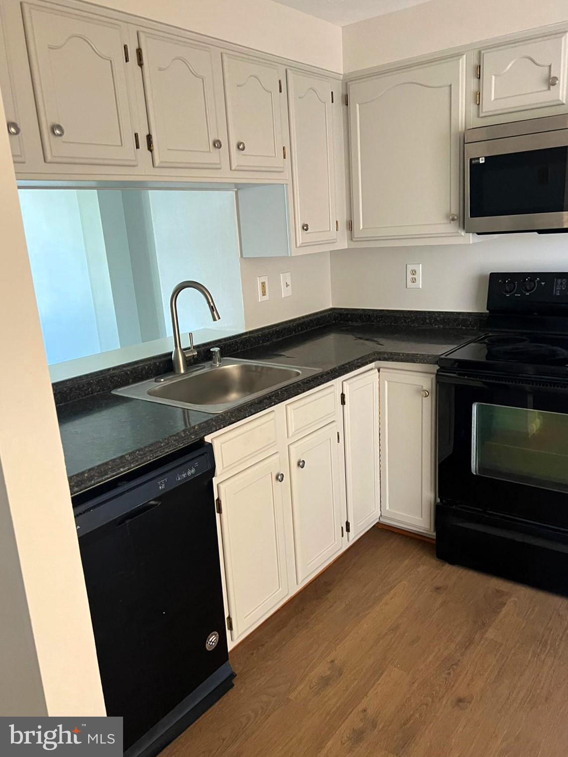 2243 Riding Crop Way Windsor Mill, MD 21244 - Photo 5 of 17 a kitchen with granite countertop white cabinets and black appliances