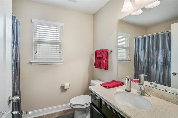 a view of a white house with a yard plants and large tree