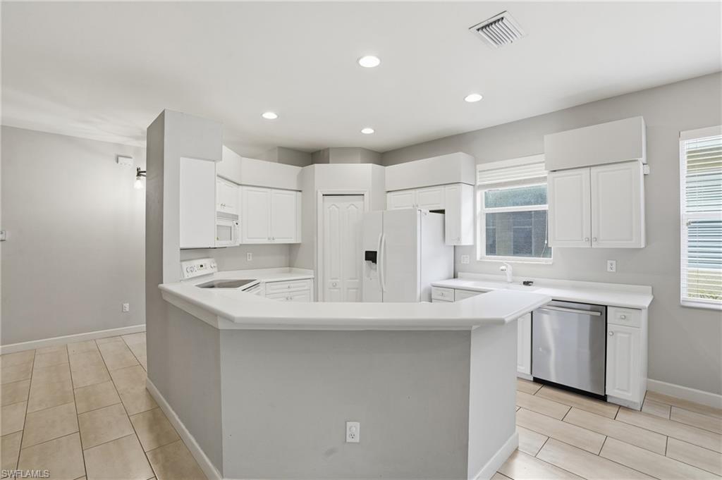 12517 Stone Valley Loop Fort Myers, FL 33913 - Photo 13 of 36 a large white kitchen with a sink and dishwasher with white cabinets