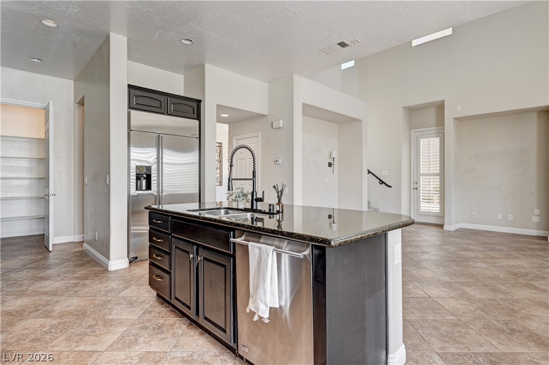 2793 Rosenhearty Drive Henderson, NV 89044 - Photo 13 of 85 A well-appointed kitchen island with dark cabinetry and granite countertops anchors this open-concept living space.