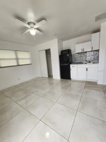a view of a refrigerator in kitchen and an empty room
