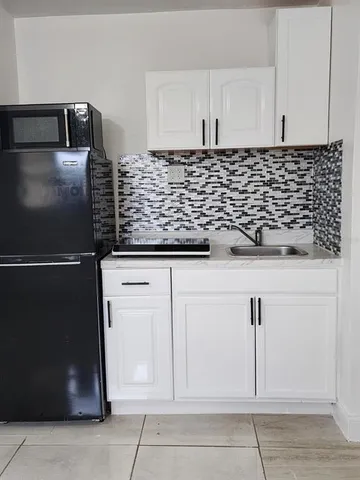 a kitchen with white cabinets and black appliances