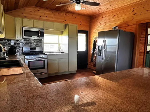 a kitchen with stainless steel appliances kitchen island granite countertop a sink window and cabinets