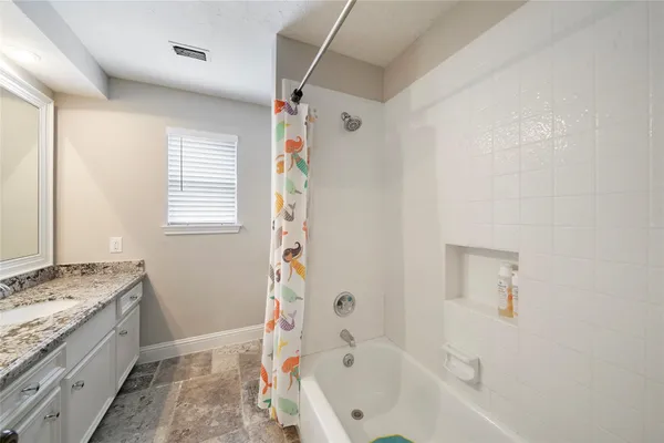 a bathroom with a granite countertop sink a bathtub and shower