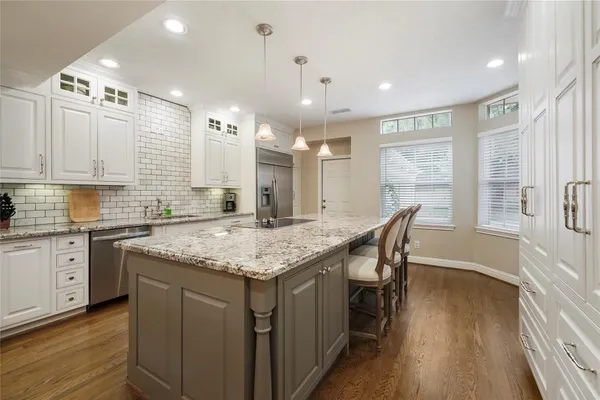 a kitchen with center island wooden floor stainless steel appliances and windows