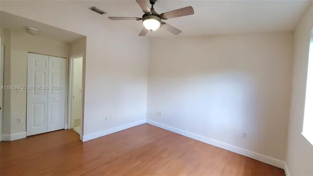 an empty room with closet and a chandelier fan
