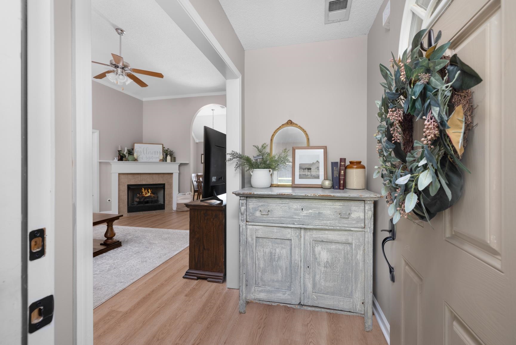 505 Terry Road Oakland, TN 38060 - Photo 5 of 40 Entryway with light wood-style flooring, a tile fireplace, ceiling fan, and ornamental molding
