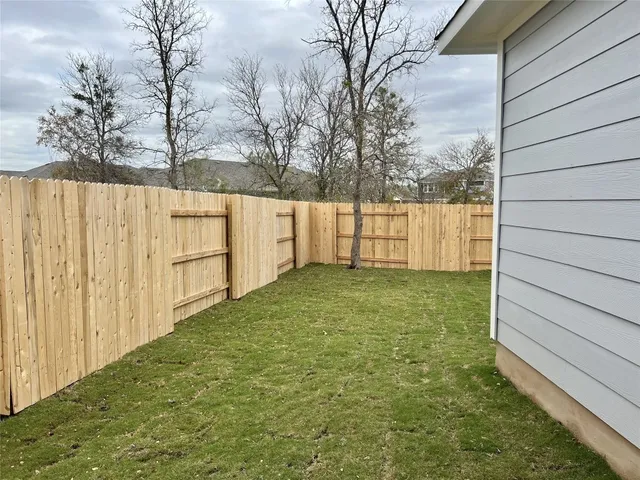 a view of backyard space with wooden fence