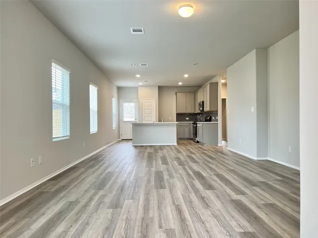 a view of empty room with wooden floor and window