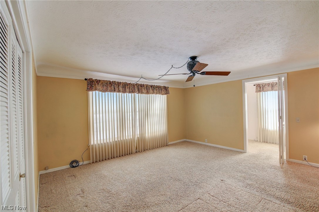 45555 North Ridge Road Amherst, OH 44001 - Photo 15 of 36 Owner's bedroom with ornamental molding, a textured ceiling, light carpet, and ceiling fan