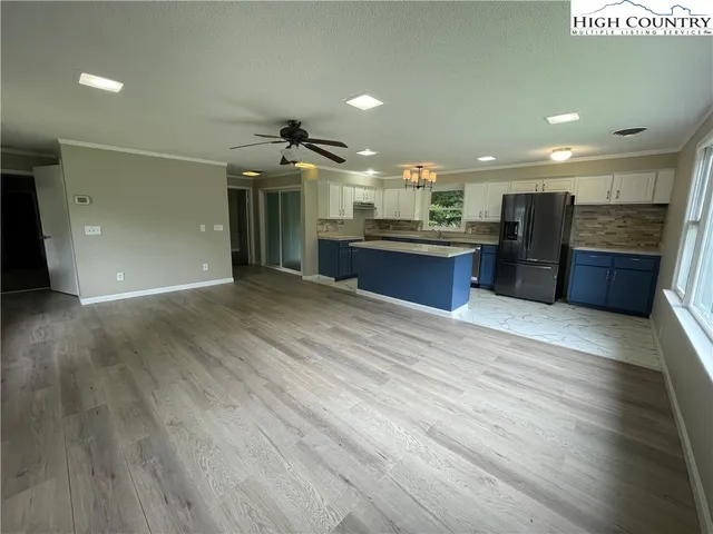 a open kitchen with stainless steel appliances kitchen island granite countertop a sink dishwasher a refrigerator and a stove with wooden floor