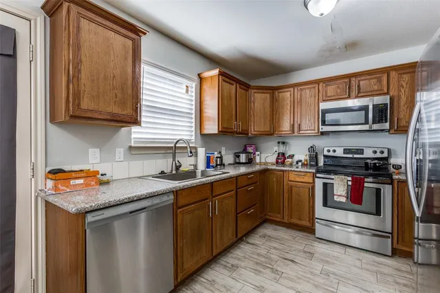 a kitchen with stainless steel appliances granite countertop a sink stove microwave and refrigerator