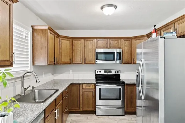 a kitchen with stainless steel appliances granite countertop a sink a stove and a refrigerator